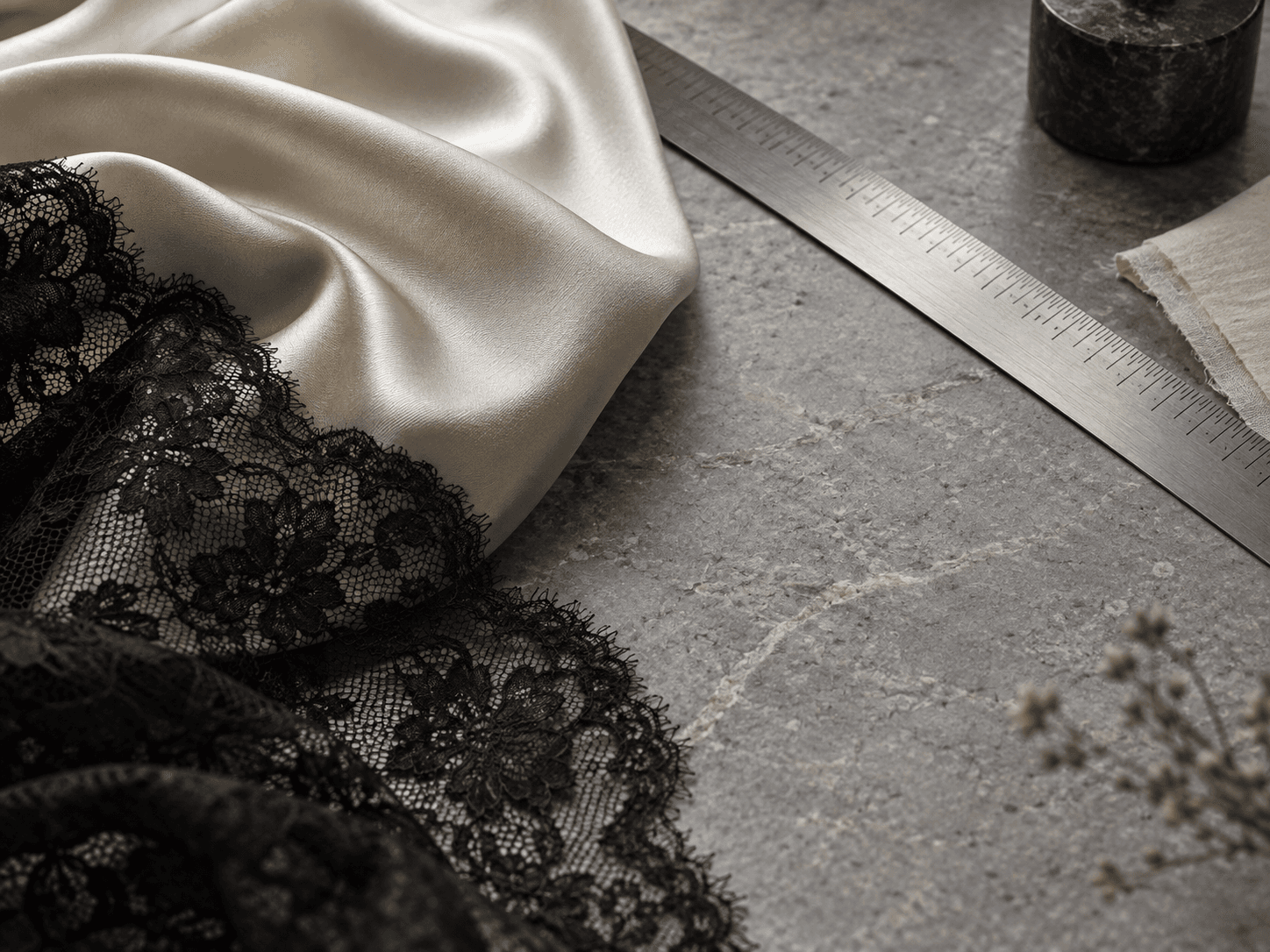 Editorial still life of ivory satin, black lace and a tailor's ruler